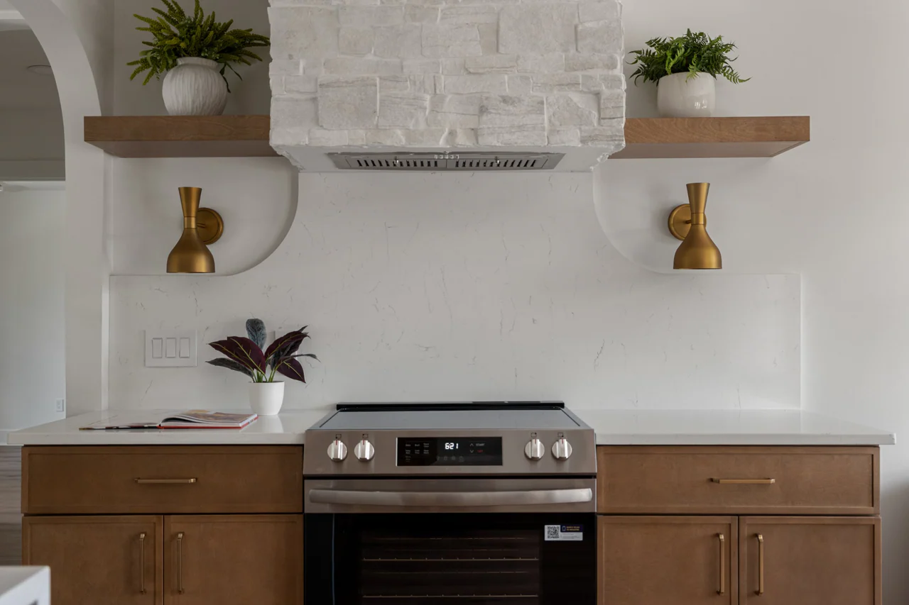 Stone range hood with brass sconces and floating shelves