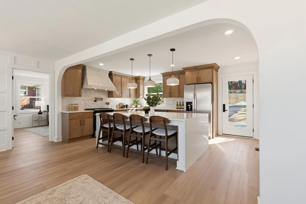 Kitchen seen through an arched opening, with island and wood cabinetry
