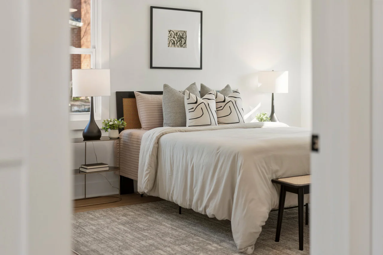 Bedroom seen through a doorway, with upholstered bed and bedside lamps