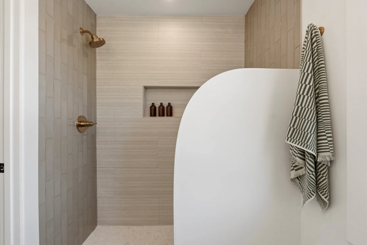 Walk-in shower with textured tile and a curved partition wall