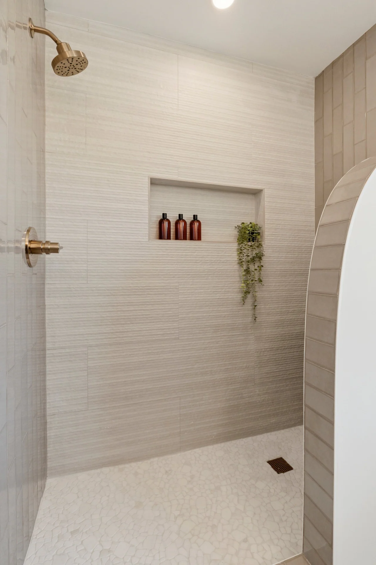 Shower with textured wall tile, niche and brass fixtures