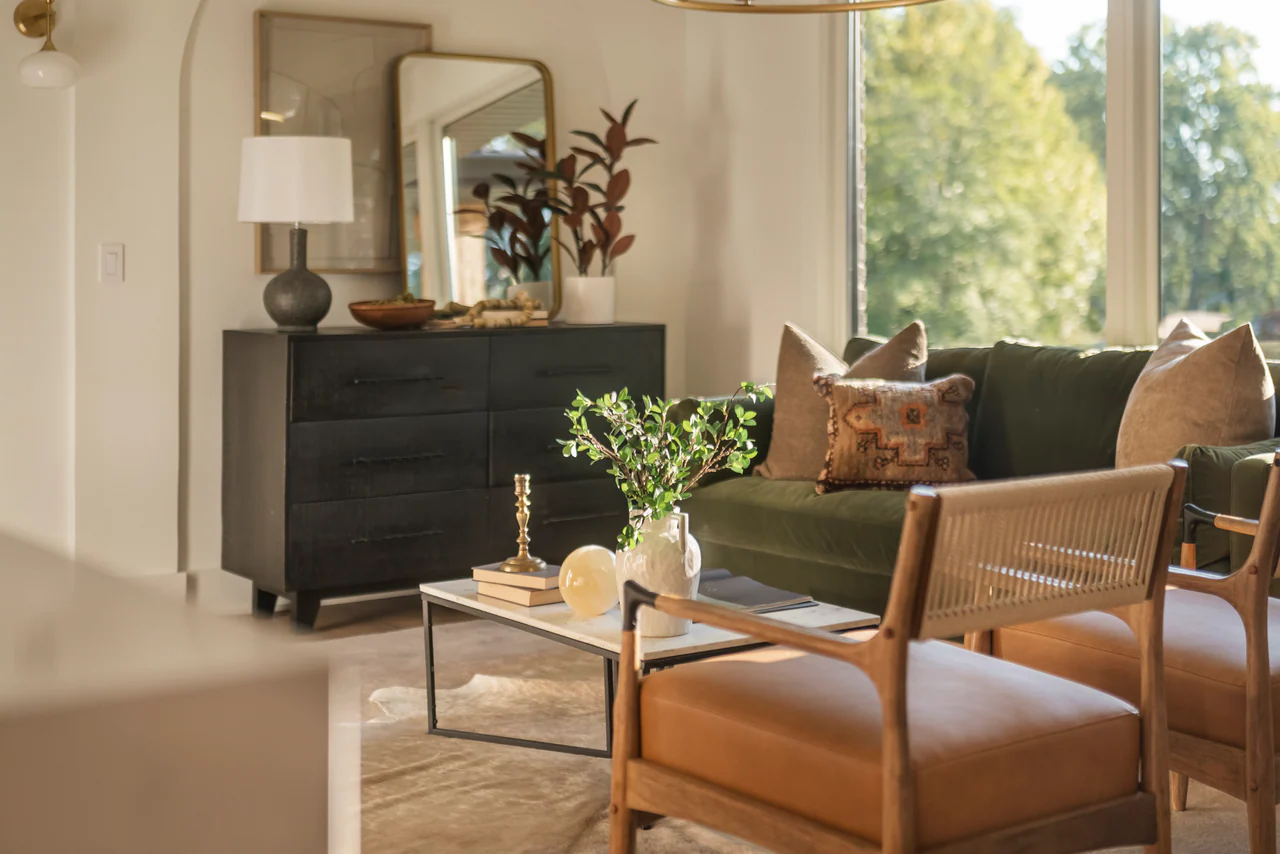 Living room with dresser, leather chairs and green sofa by a large window