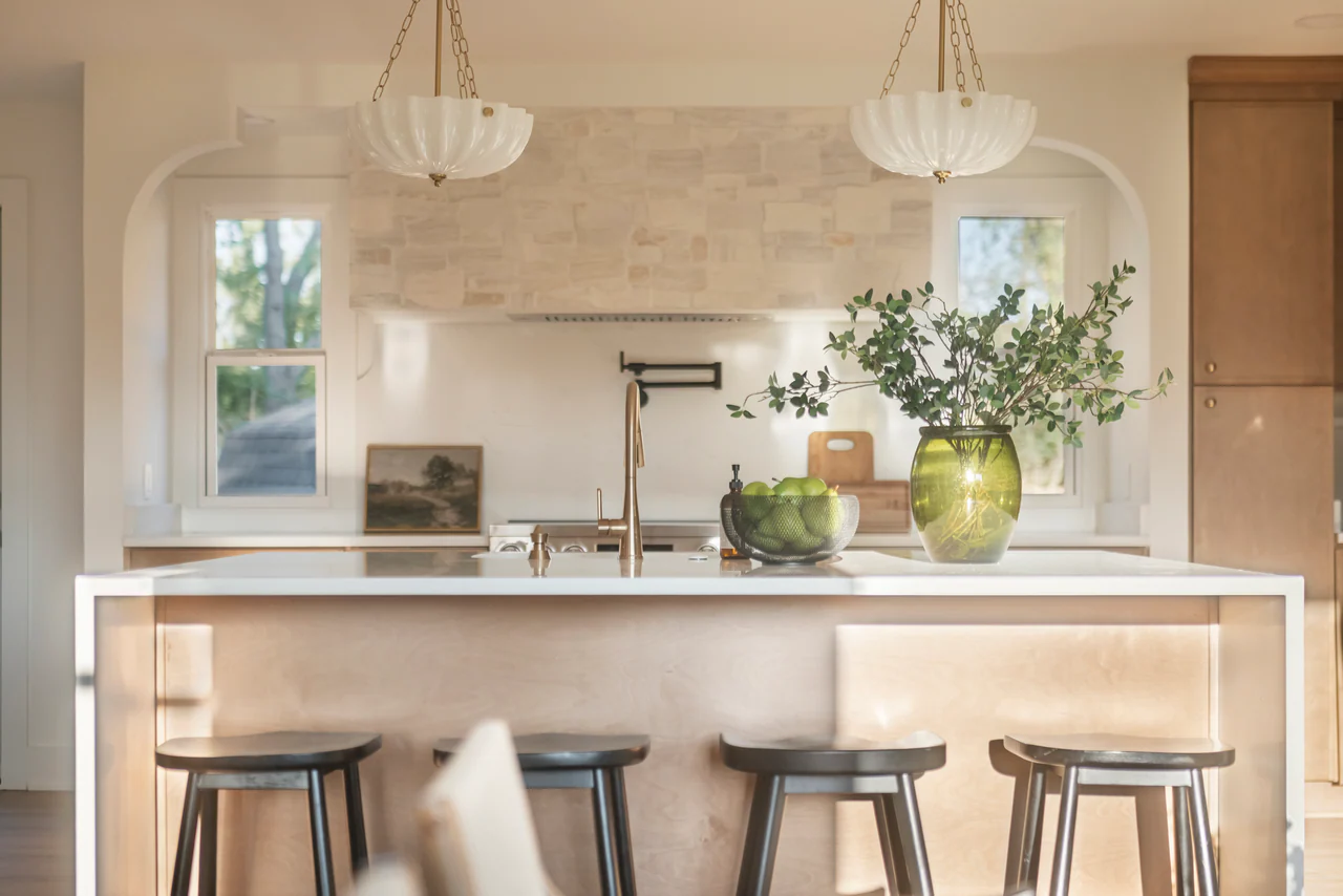 Kitchen island with scalloped pendants and stone range hood in an arched alcove