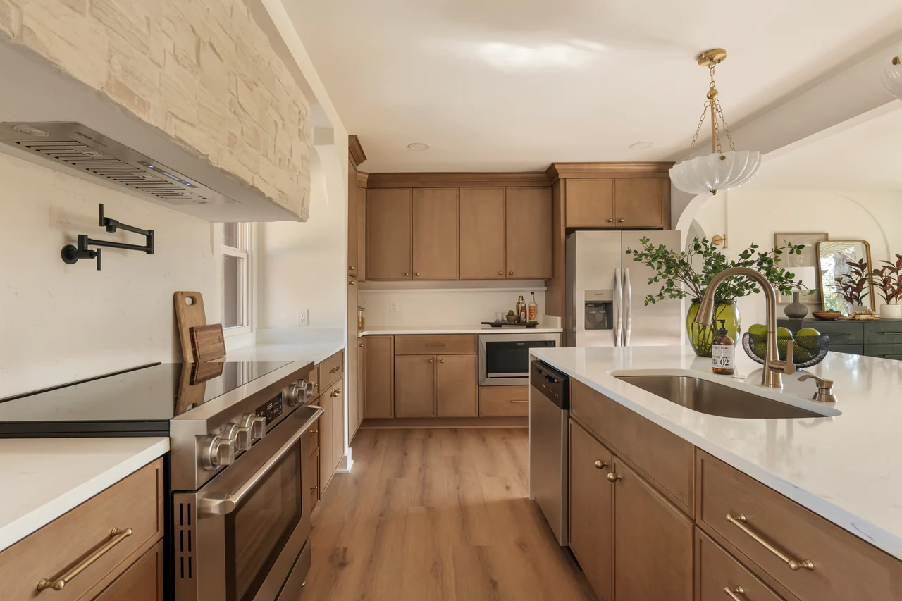 Kitchen with stained wood cabinetry, stone hood and brass fixtures