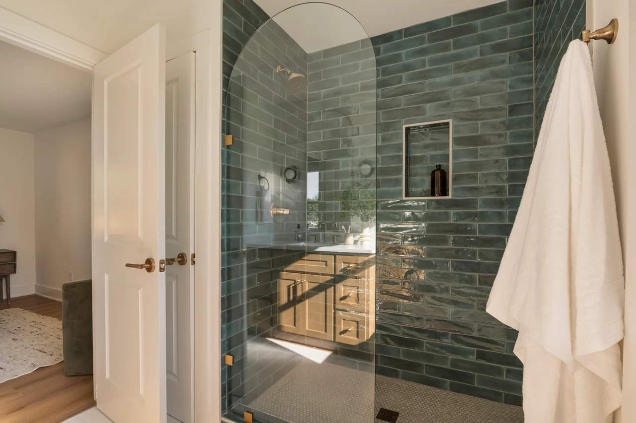 Bathroom with green tile and arched glass shower panel